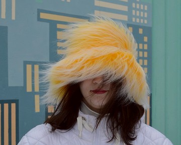 黃色人造毛皮漁夫帽。節日模糊的霓虹燈帽。狂歡的帽子。明亮的毛茸茸的帽子