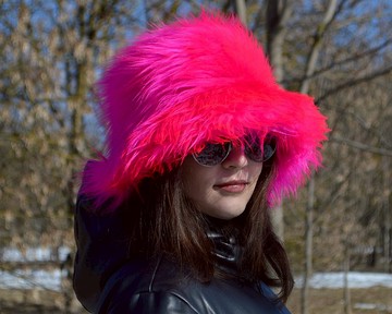 人造毛皮漁夫帽。霓虹粉色帽子。紫紅色蓬鬆的帽子。明亮的毛茸茸的帽子。