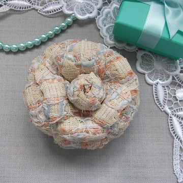 牛奶白織物山茶花胸針，綴有藍色纖維