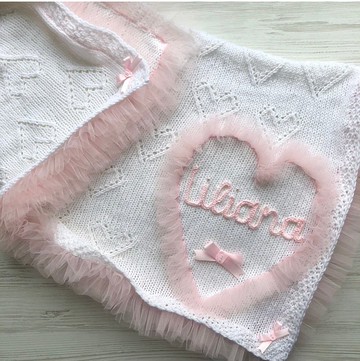 帶粉色薄紗和嬰兒名字的白色毯子。
