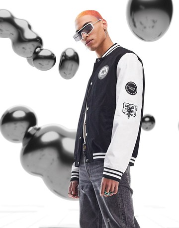 ASOS DESIGN oversized varsity jacket in black with badging and contrast sleeves