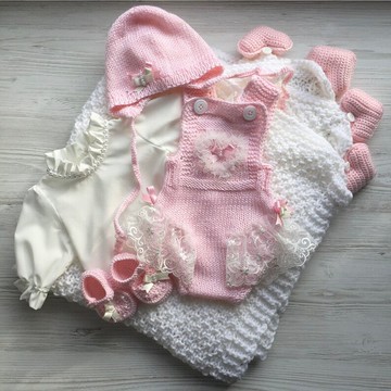 粉色針織連身衣、帽子短靴、襯衫和白色毯子，上面有四顆粉紅色的心。