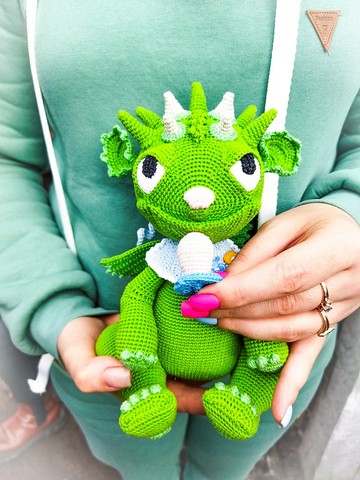 带奶嘴的龙宝宝。 绿色宝贝龙玩具amigurumi钩编。 可爱的娃娃